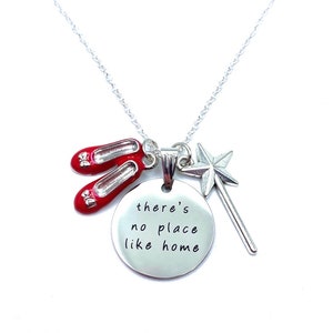 May include: Silver necklace with a charm that says "there's no place like home" and features a red pair of ruby slippers and a silver star wand.