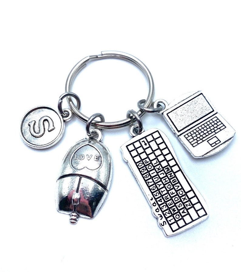 May include: Silver keychain with a computer mouse, keyboard, laptop, and letter S charm. The mouse has a heart with the word "LOVE" on it. The keyboard has the numbers 1-9 and the letters of the alphabet.