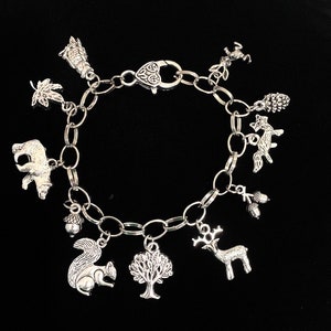 May include: A silver charm bracelet with a variety of woodland animal and nature charms, including a bear, squirrel, deer, fox, tree, acorn, and pine cone.