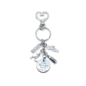 May include: Silver keychain with a running figure, a shoe, a water bottle, and a tag that says "Gotta Run". The main charm is a round tag with the text "I run like a girl. Try to keep up."