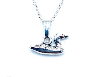 May include: A silver chain necklace with a loon pendant. The loon is a bird that is often associated with lakes and water.