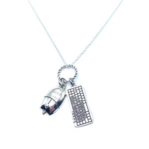 May include: Silver-toned necklace featuring a computer mouse charm with the word "LOVE" and a keyboard charm. The keyboard charm has the letters and numbers of a keyboard. The necklace is on a white background.