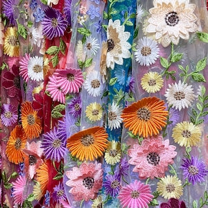 May include: A colorful fabric with embroidered flowers in various shades of pink, purple, orange, and yellow. The fabric has a sheer, mesh-like texture.