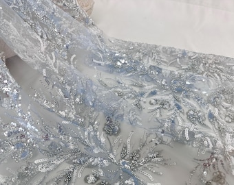 Puede incluir: Tela de tul azul claro con lentejuelas y cuentas plateadas en un patrón floral.
