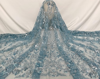 Puede incluir: Tela azul claro con lentejuelas y un patrón floral plateado. La tela es transparente y tiene una textura delicada.