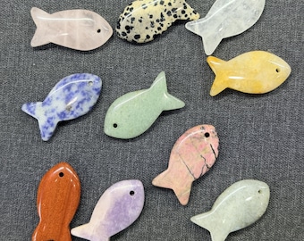 May include: A collection of carved stone fish in various colors and patterns. The fish are in shades of pink, purple, green, yellow, and orange, with some featuring speckled or marbled designs. Each fish has a small hole near the top.