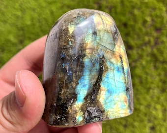May include: A polished, freeform labradorite crystal with iridescent blue, green, and gold hues. The crystal has a smooth, rounded surface and a natural, irregular shape.