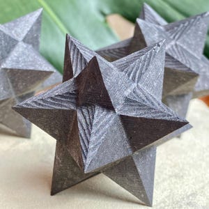 May include: Close-up of several gray, star-shaped decorative objects. Each star has multiple points and a textured surface. The stars are arranged in a group, with some in focus and others blurred in the background.