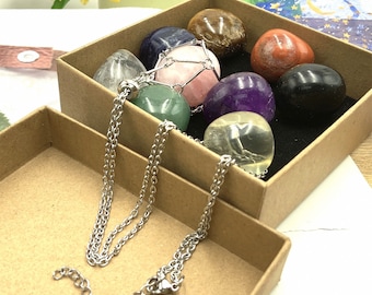 May include: A set of seven chakra stones in a brown box with a silver chain necklace. The stones are clear quartz, amethyst, tiger's eye, red jasper, black obsidian, green aventurine, and citrine.