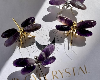 May include: Four amethyst dragonfly sculptures with gold and silver accents. The dragonflies are arranged on a white surface with the text "Jingy Crystal @Etsy" visible in the lower right corner.