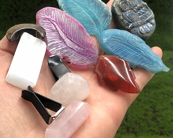 May include: Assortment of colorful crystal car air fresheners, including a pink, purple, and blue feather design, a red heart shape, a white crystal, and a clear crystal.  There is also a black car air freshener clip.