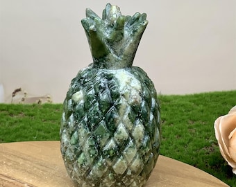 May include: A green and white carved pineapple sculpture. The pineapple is made of a green stone with white veins running through it. The sculpture is about 6 inches tall.
