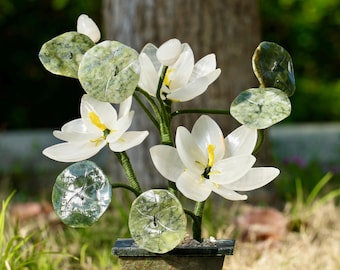 May include: A jade green and white stone lotus flower sculpture in a jade green planter. The sculpture features multiple lotus flowers and leaves.