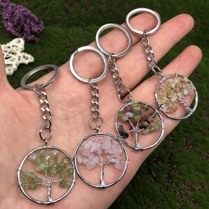 May include: Four silver keychains with different colored gemstone tree of life charms. The charms are made of wire wrapped around small stones. The stones are green, pink, multi-colored, and yellow.