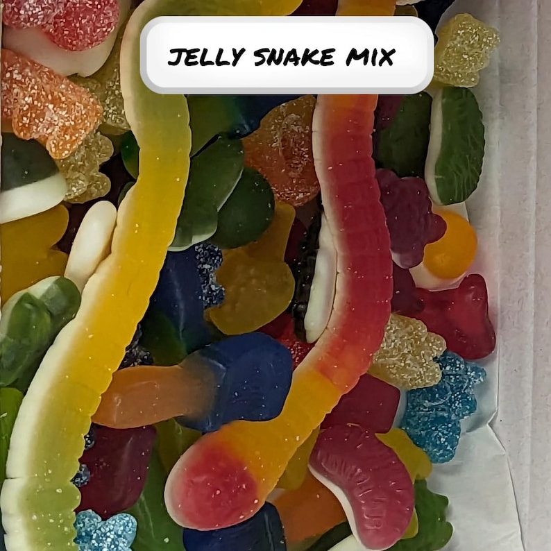 Peut inclure: Gros plan sur une vari&eacute;t&eacute; de bonbons g&eacute;lifi&eacute;s color&eacute;s, y compris des serpents g&eacute;lifi&eacute;s, dans un r&eacute;cipient transparent. L'&eacute;tiquette sur le r&eacute;cipient indique "Jelly Snake Mix".