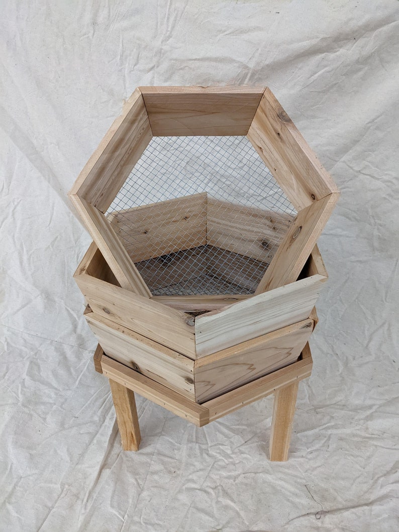 May include: A wooden hexagonal planter with three tiers and a wire mesh insert. The planter is on a stand with four legs.