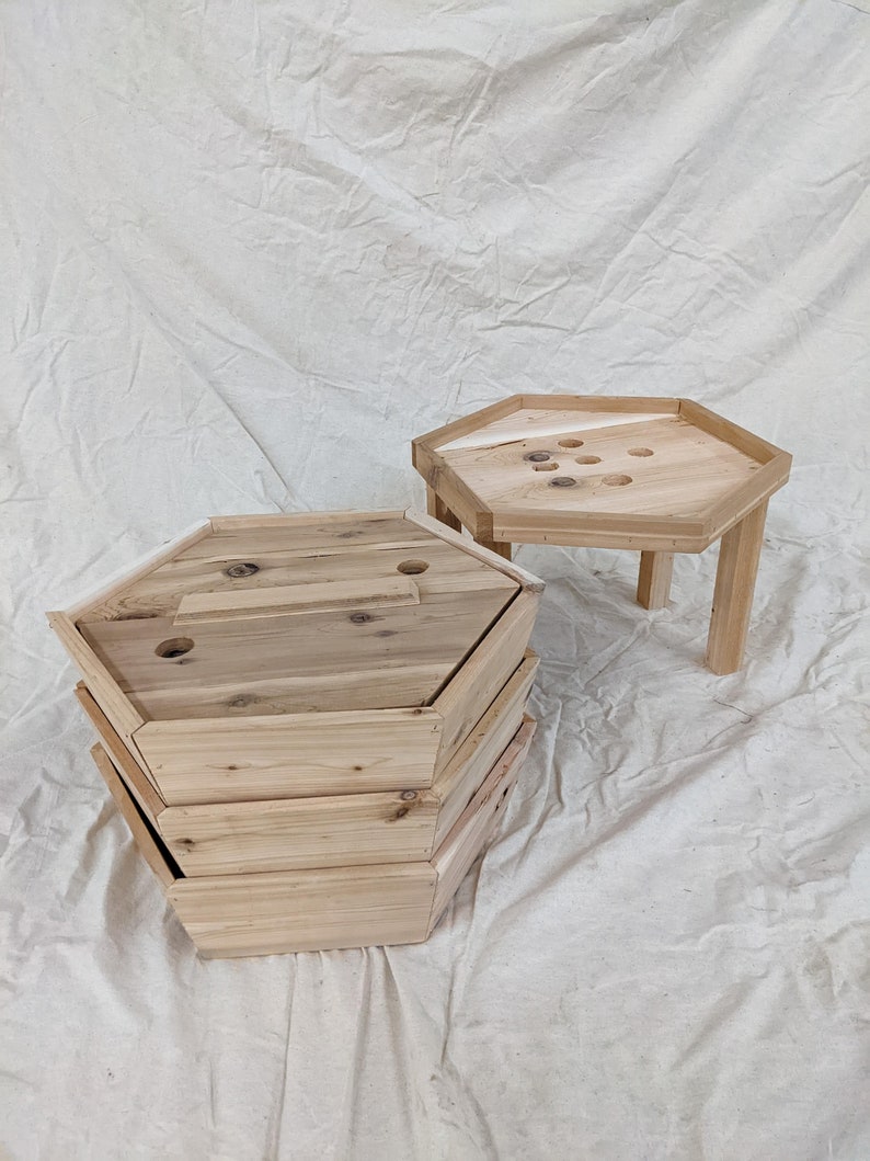May include: A set of four wooden hexagonal nesting tables. The tables are made of natural wood and have a rustic finish. The top table has a small hole in the center.