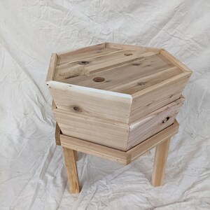 May include: A wooden hexagonal planter with three tiers and four legs. The planter is made of natural wood and has a rustic look.