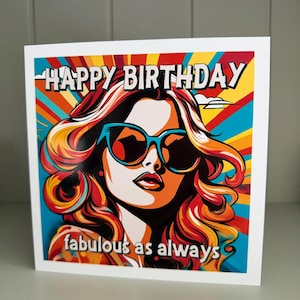 May include: A square birthday card with a pop art style illustration of a woman wearing sunglasses. The card features the text "HAPPY BIRTHDAY" at the top and "fabulous as always" at the bottom, set against a colorful background of radiating lines.