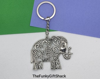 Puede incluir: Llavero de elefante plateado con un diseño filigranado detallado. El elefante tiene la trompa enroscada y un anillo en la parte superior para sujetar las llaves.
