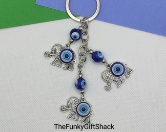 May include: Silver key chain with three blue and white evil eye elephant charms and three blue evil eye beads.
