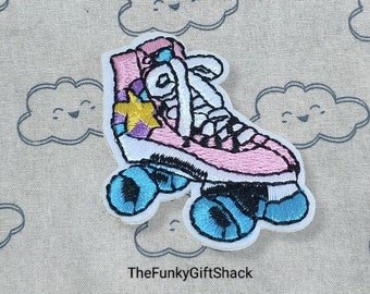 May include: Pink and white roller skate with a yellow star embroidered on the side. The skate is on a light brown fabric background with a repeating pattern of white clouds with smiling faces.