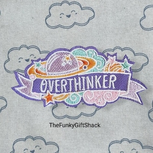 May include: Purple and orange embroidered iron-on patch with a planet and stars, and the text "Overthinker".