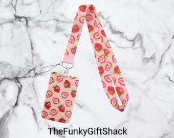 May include: A pink lanyard with a white and red strawberry print. The lanyard has a matching pink ID card holder with a silver clip.