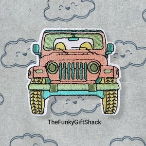 May include: Embroidered iron-on patch of a pink Jeep with a green grille and yellow tyres, driving over a blue cloud with a smiling face. The text "TheFunkyGiftShack" is below the Jeep.