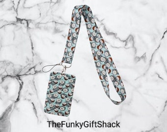 May include: A blue and white lanyard with a coconut pattern. The lanyard has a matching ID card holder with a coconut pattern. The text "TheFunkyGiftShack" is printed below the lanyard.