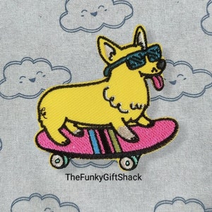 May include: Yellow embroidered patch of a corgi wearing sunglasses and riding a pink skateboard with rainbow wheels. The text "TheFunkyGiftShack" is below the image.