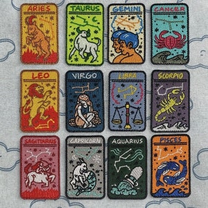 May include: Twelve colourful embroidered patches featuring the astrological signs of the zodiac. Each patch is rectangular and features a different zodiac symbol, including Aries, Taurus, Gemini, Cancer, Leo, Virgo, Libra, Scorpio, Sagittarius, Capricorn, Aquarius, and Pisces.