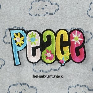 May include: A colourful embroidered patch with the word "peace" in a retro font. The letters are outlined in black and decorated with colourful flowers.
