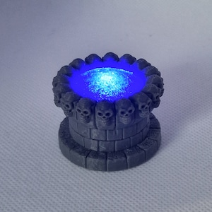May include: A small, gray, stone well with a blue glowing liquid inside. The well is decorated with a ring of skulls around the top.