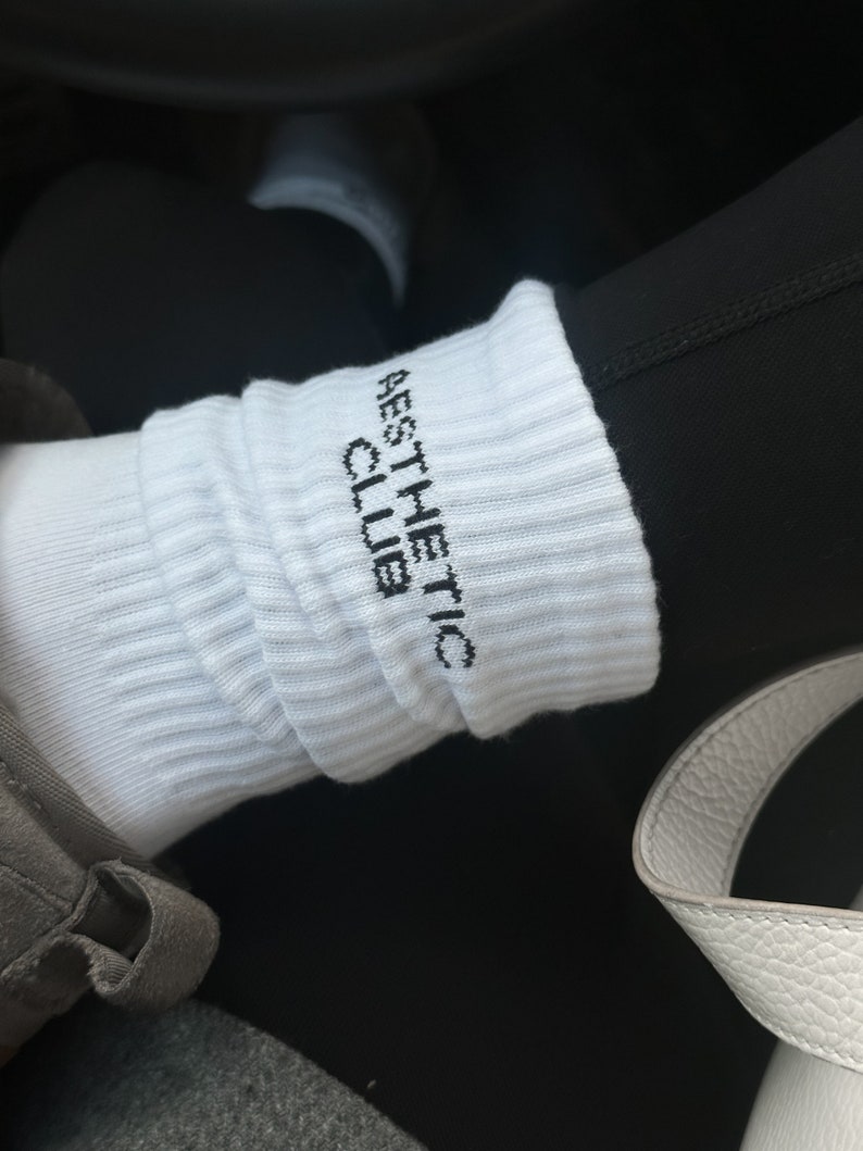 May include: White socks with black text that reads "AESTHETIC CLUB".