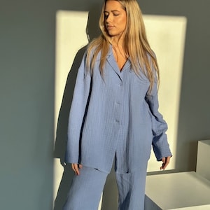 May include: A light blue pajama set with a long-sleeved shirt and wide-leg pants. The shirt has a button-up front and a pocket on the left side.