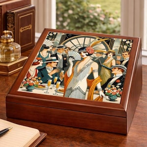 May include: A wooden jewelry box with a decorative lid featuring a vintage illustration of a 1920s party scene. The box is brown and sits on a wooden surface, with books and a perfume bottle in the background.
