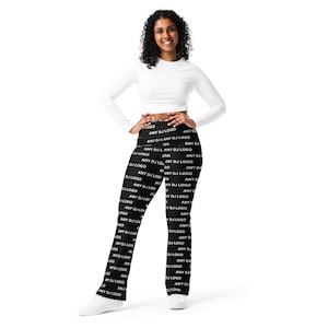 Puede incluir: Una mujer con un top blanco de manga larga y leggings negros. Los leggings están cubiertos con el texto blanco "ANY DJ LOGO". Los leggings son ajustados y de cintura alta.