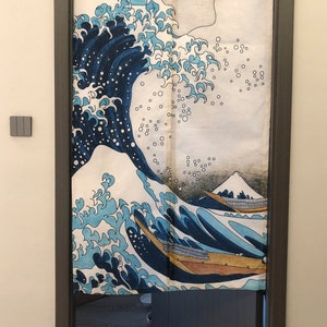 May include: A white canvas door curtain with a blue and white wave design. The wave design is reminiscent of the Great Wave off Kanagawa by Hokusai. The curtain is hanging in a doorway with a black cat standing in the doorway.