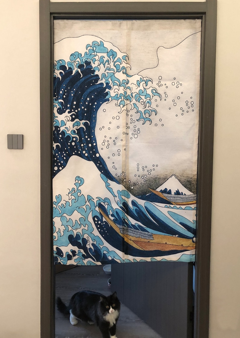 May include: A white canvas door curtain with a blue and white wave design. The wave design is reminiscent of the Great Wave off Kanagawa by Hokusai. The curtain is hanging in a doorway with a black cat standing in the doorway.