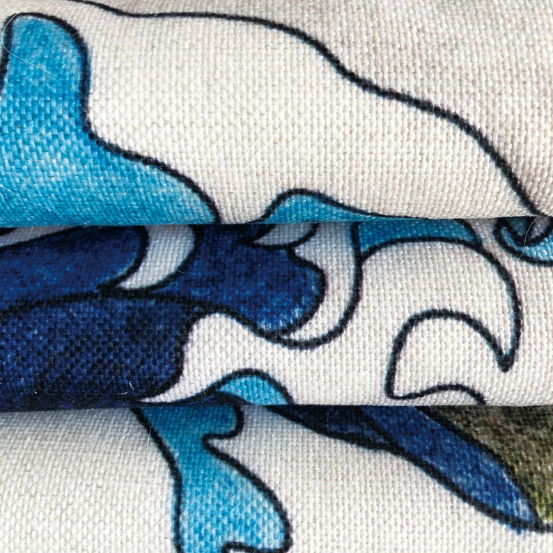 May include: Close-up of a white fabric with a blue and black floral pattern. The fabric is folded in thirds, showing the pattern on each layer.