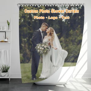 May include: A custom shower curtain featuring a printed photograph of a couple in wedding attire standing in a grassy field. The text Custom Photo Shower Curtain and Photo Logo Text is printed in orange at the top of the curtain with metal grommets.