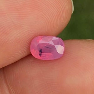 May include: A pink oval-shaped gemstone with a faceted cut.