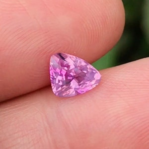 以下が含まれることがあります： ファセットカットされたピンクの三角形の宝石。宝石は薄いピンクの色合いで、わずかに紫がかった色合いがあります。