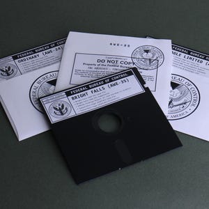 May include: A black 5.25-inch floppy disk labeled Federal Bureau of Control Bright Falls (AWE-35) resting on three white envelopes. Each envelope features the Federal Bureau of Control seal and text including Ordinary (AWE-24) and Eagle Limited (AWE-44).