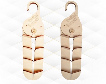 May include: Two wooden folding hangers with the text "Folding hangers" engraved on the top. The hangers are light brown and have a hook at the top. The bottom portion of the hanger folds up.