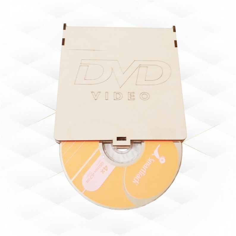 May include: A wooden DVD case with the words "DVD VIDEO" engraved on the front. The case is open and a blank DVD disc is visible inside. The disc is orange with the word "SmartMedia" printed on it.