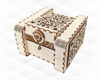May include: A light-colored wooden box with intricate laser-cut floral patterns on the top and sides. The box features a small drawer and a circular lock mechanism. The design is detailed and the wood has a natural finish.