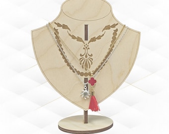May include: A wooden necklace display stand with a heart-shaped base and a decorative cutout design. Two necklaces with pendants are displayed on the stand. One necklace has a silver pendant with a star design and the other has a red pendant with a cross design. The necklaces have a gold chain and a silver chain.
