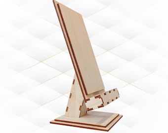 May include: Wooden phone stand with a natural finish. The stand has a triangular base and a rectangular platform for holding a phone.